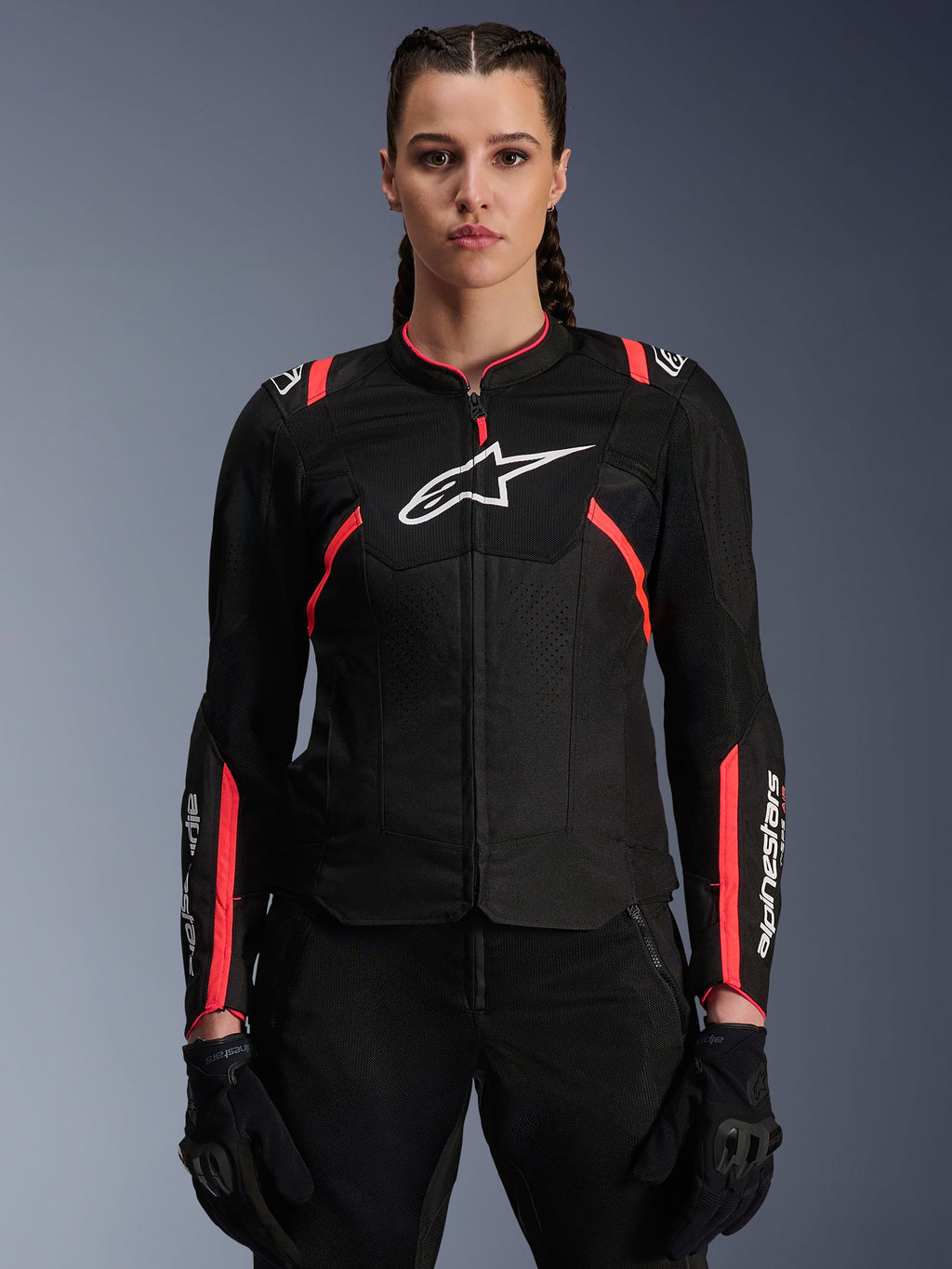 Alpinestars Woman Stella T-Sps Air V2 Jacket, textiele motorjas, zwart met Diva Pink accenten, ademende mesh-panelen en roze details, wit Alpinestars-logo op de borst, vrouwelijk model draagt zwarte motorbroek en handschoenen