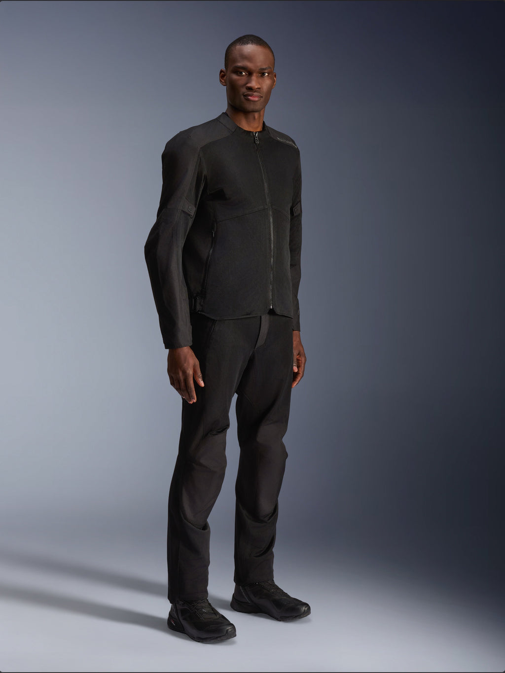 Alpinestars C-1 Air Jacket, zwart, gedragen door een model met bijpassende zwarte motorbroek en schoenen, voorzien van grote tech mesh panelen voor luchtstroom, strakke urban esthetiek met een gestroomlijnde pasvorm