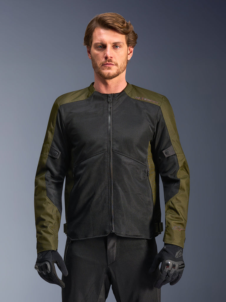 Alpinestars C-1 Air Jacket, Khaki en zwart, motorjas voor heren met grote tech mesh-panelen voor maximale luchtstroom, gedragen door een model met zwarte motorbroek en handschoenen, urban eigentijds design voor woon-werkverkeer.
