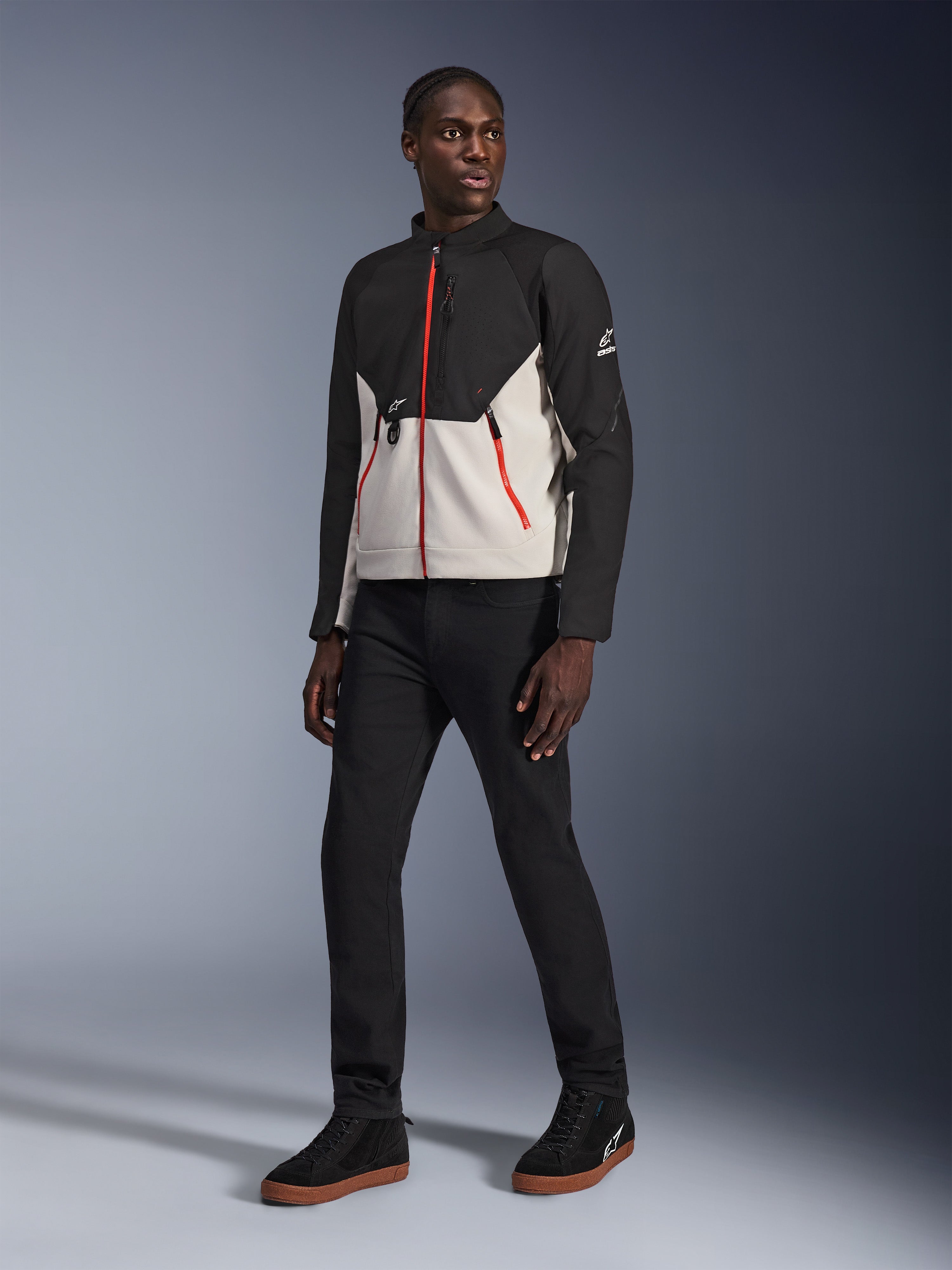 Alpinestars Provoke Jacket in Black Metal Gray, motorjas met kenmerkende rode ritsen aan de voorzijde en op de zakken, gecombineerd met zwarte broek en zwarte high-top sneakers met gumzolen, urban eigentijdse motoruitrusting voor een street-ready look, model draagt de jas
