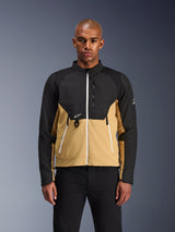 Alpinestars Provoke Jas, urban motorjas, zwart en camel, vooraanzicht op een mannelijk model, tweekleurig ontwerp met witte ritsen, borstzak met rits en D-ring en klein wit Alpinestars-logo, eigentijdse motorkleding voor de stad.
