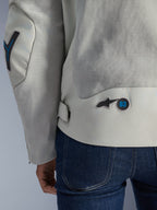Alpinestars Circal-1 Air Jacket in Metal Gray met Methyl Blue accenten, gedetailleerd achteraanzicht met gerecyclede mesh ventilatiepanelen en een ronde '63' logo-badge, gedragen met blauwe jeans.
