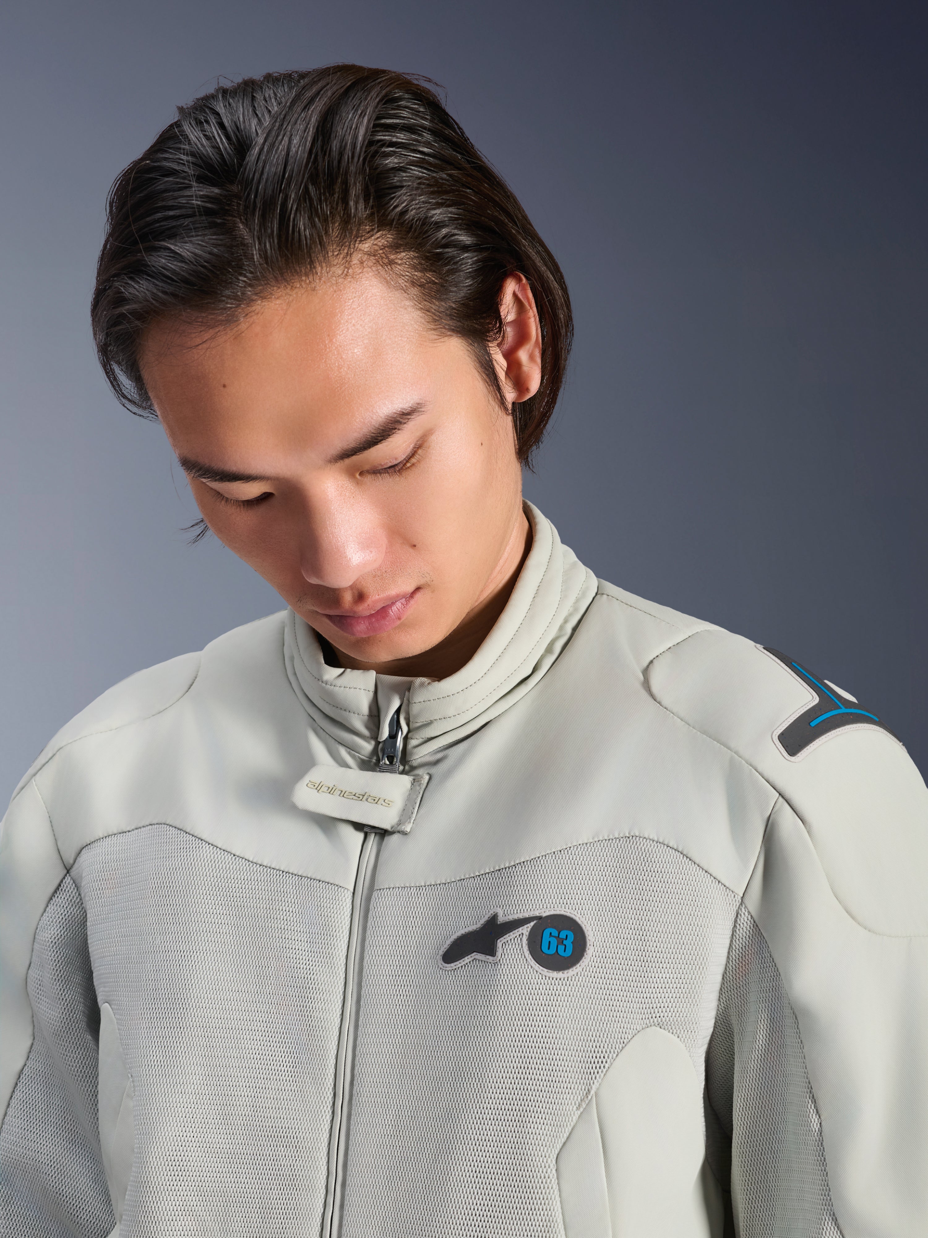Mannelijk model draagt de Alpinestars Circal-1 Air Jacket in Metal Gray met Methyl Blue accenten, close-up weergave van de kraag, mesh borstpanelen en minimalistische logo-branding, duurzame stedelijke motoruitrusting.