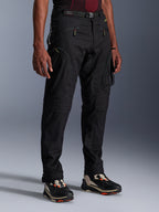 Alpinestars Acteon broek, zwarte motorbroek, gedragen door een model, met een modern taps toelopend silhouet, cargozakken met ritssluiting, verstelbare tailleriem en technische sneakers, stedelijke motorkleding