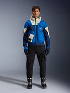 Alpinestars Mogress Air Jacket, Blue Almond urban motorjas, gedragen met een zwarte broek en laarzen, voorzien van een color-blocked blauw en crème technisch ontwerp met utility-zakken en een capuchon, eigentijdse op streetwear geïnspireerde motorkleding
