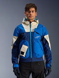 Alpinestars Mogress Air Jacket in Blue Almond, urban motorjas met capuchon, contrasterende blauwe en gebroken witte panelen, utility-zakken en een groenblauwe rits aan de voorzijde, gedragen door een model met zwarte broek en handschoenen