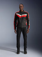 Alpinestars T-Dyno Air Jacket, textiel motorjas, zwart, helderrood en ecru, gedragen door een model met zwarte broek en laarzen, vintage-geïnspireerd ontwerp met opvallende kleurstrepen op de borst, sterlogo's op de mouwen en ademende mesh-constructie voor urban rijden.