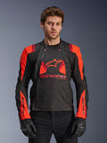 Alpinestars T-Stunt Air Jacket, textiele motorjas, zwart, fluorescerend rood en donkerrood, voorzien van groot sterlogo en mesh-panelen voor ventilatie, gedragen door model met zwarte handschoenen