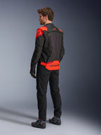 Alpinestars T-Stunt Air Jacket van achteren gezien, zwart, fluorood en donkerrood, textiel motorjas met mesh-panelen en sportieve snit, met opvallende Alpinestars-branding op de onderrug, man draagt de jas met een zwarte broek en motorlaarzen