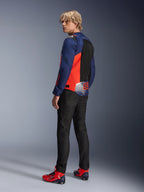 Alpinestars MM93 T-SPS Air V2 Jas, Blue Navy en Red Fluo, gedragen door een model vanaf de achterkant met zwarte motorjeans en bijpassende rood-blauwe schoenen, voorzien van mesh-panelen en Marc Márquez 93 branding.