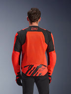 Alpinestars MM93 T-SPS Air V2 Jas, achteraanzicht, fluo rood en zwart, met 93-racelogo op de nek, groot mesh-paneel op de rug voor luchtstroom, achterflap onderaan met Alpinestars-sterlogo en geometrische strepen, gedragen met een zwarte broek en motorhandschoenen