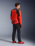 Alpinestars MM93 T-SPS Air V2 Jas in Red Fluo en Black, driekwart achteraanzicht op een model, met Marc Marquez 93-branding op de kraag en onderrug, gecombineerd met een zwarte broek en rode motorschoenen.