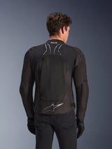 Alpinestars SMX Air Jas in Black Anthracite, achteraanzicht op een model, voorzien van een groot tech mesh rugpaneel voor ventilatie, Tech-Air Ready-branding op de kraag en een zilveren Astar-logo op de onderrug, gecombineerd met zwarte handschoenen en een motorbroek.