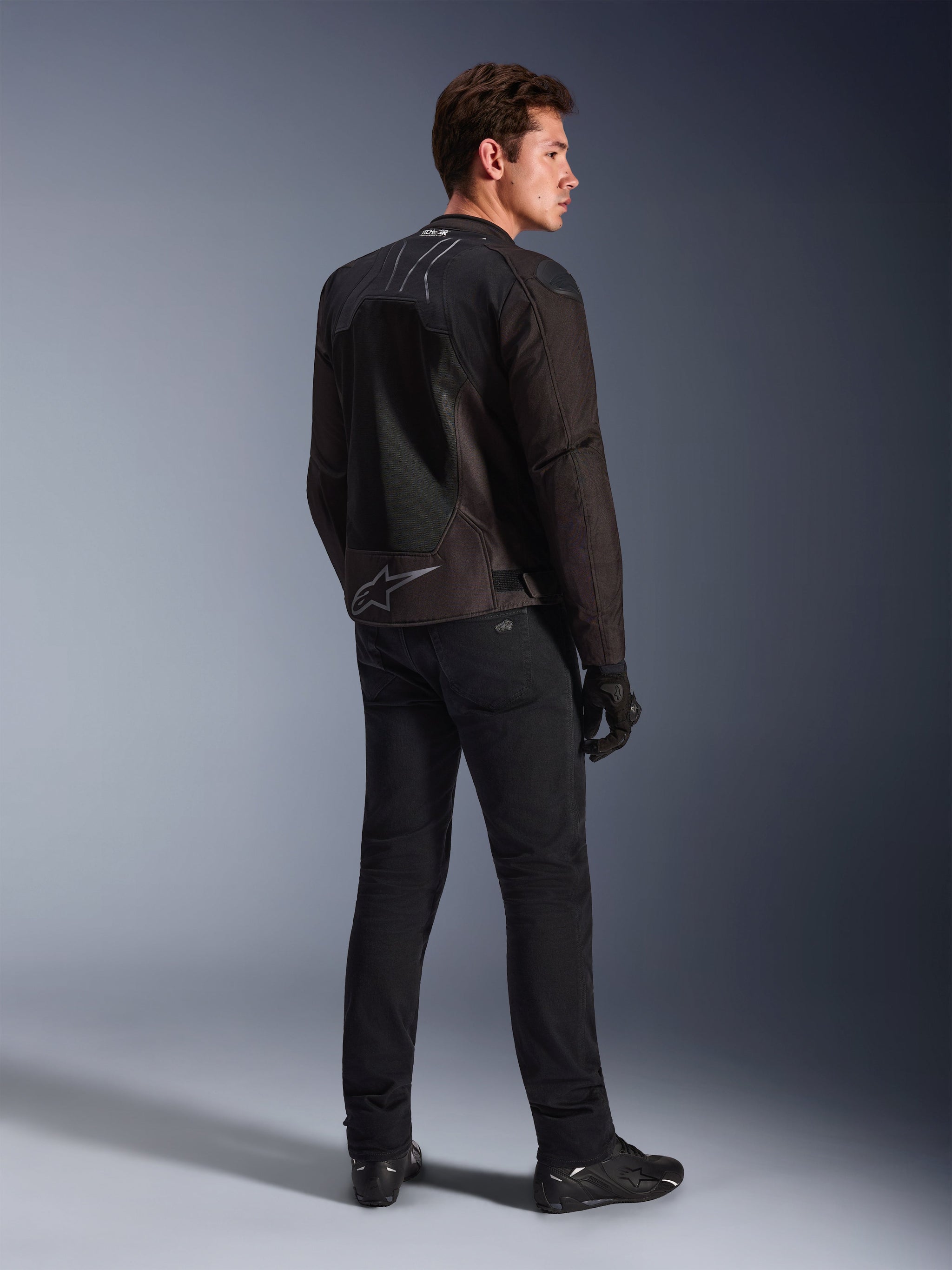 Alpinestars SMX Air motorjas in Black Anthracite, achteraanzicht op model, met Tech-Air® Ready-branding op de kraag en Astar-logo op de onderrug, gedragen met zwarte motorbroek en schoenen.