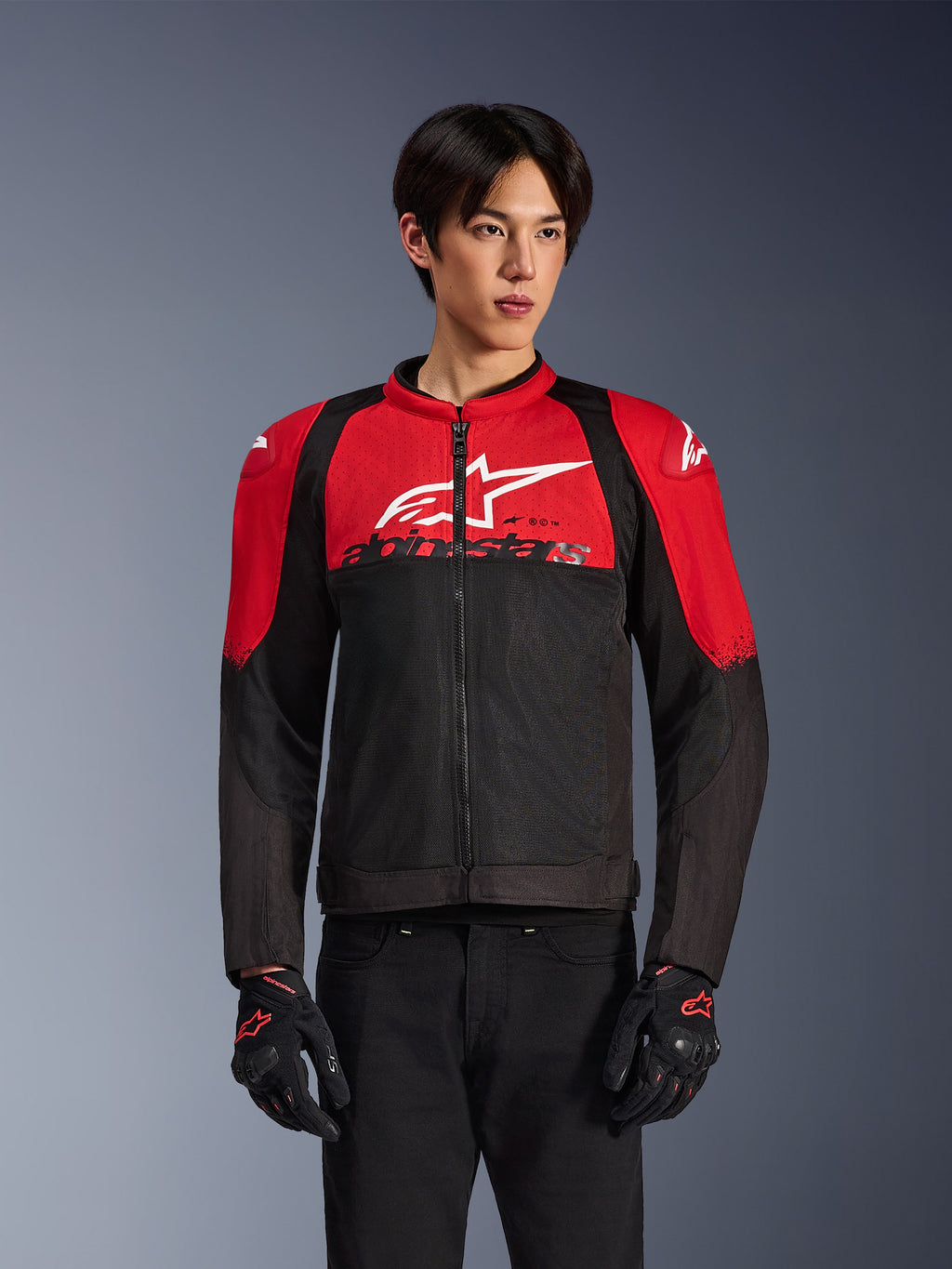Alpinestars SMX Air Jacket, Motorcycle Mesh Jacket, Bright Red and Black, worn by a model with black riding gloves, featuring a large white logo on the chest, ventilated textile construction with red shoulder panels and black sleeves, sporty performance gear for warm-weather riding