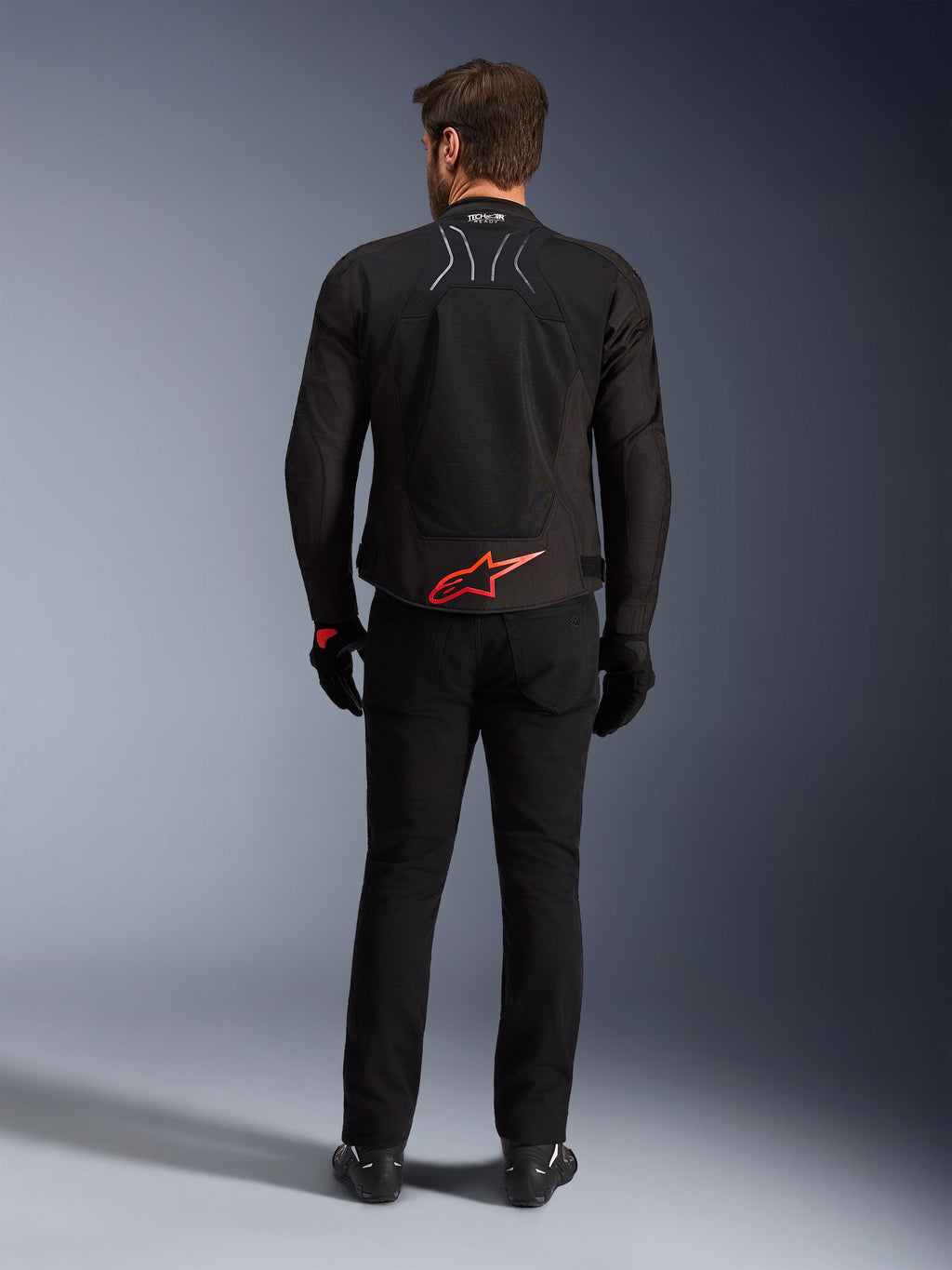 Alpinestars SMX Air Jacket, zwart met felrood logo, achteraanzicht met Tech-Air Ready branding en mesh ventilatiepanelen, gedragen met zwarte broek en handschoenen, hoogwaardige sport- en race-motoruitrusting