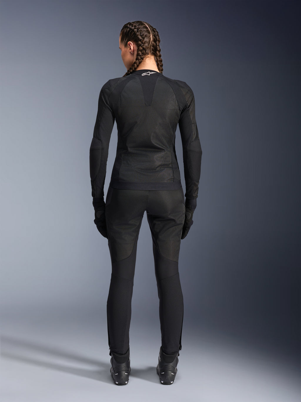 Alpinestars Stella Troop-Air jas, motorjas voor dames, zwart, achteraanzicht van een rijder die een technische mesh jas draagt, gecombineerd met bijpassende zwarte motorbroek, handschoenen en laarzen, nauwsluitend ademend ontwerp met een wit Alpinestars-logo op de kraag