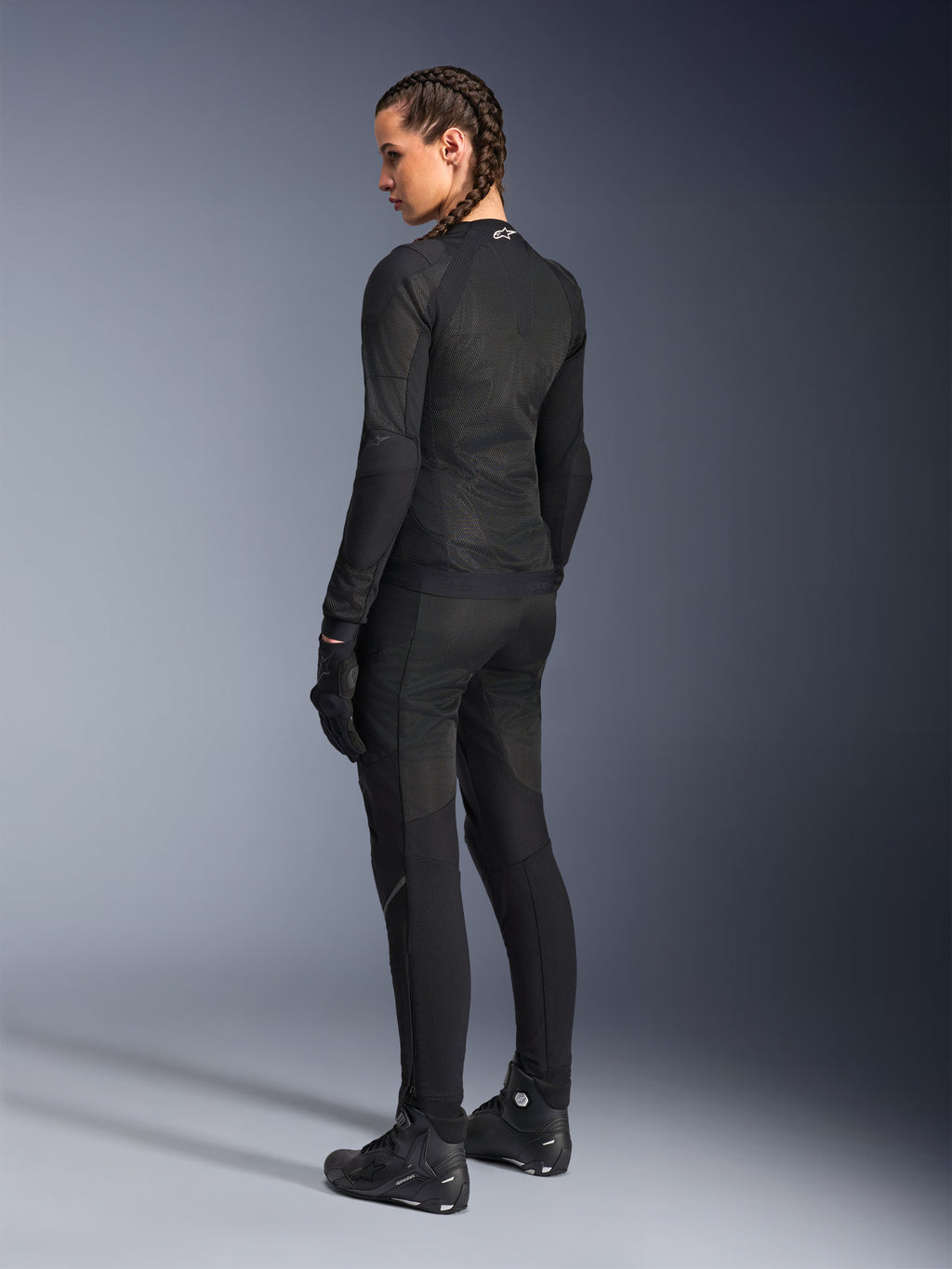 Alpinestars Stella Troop-Air motorjas voor dames, zwart, achteraanzicht, gedragen met bijpassende zwarte motorbroek, handschoenen en laarzen, slim-fit technische mesh-constructie voor rijden in de stad