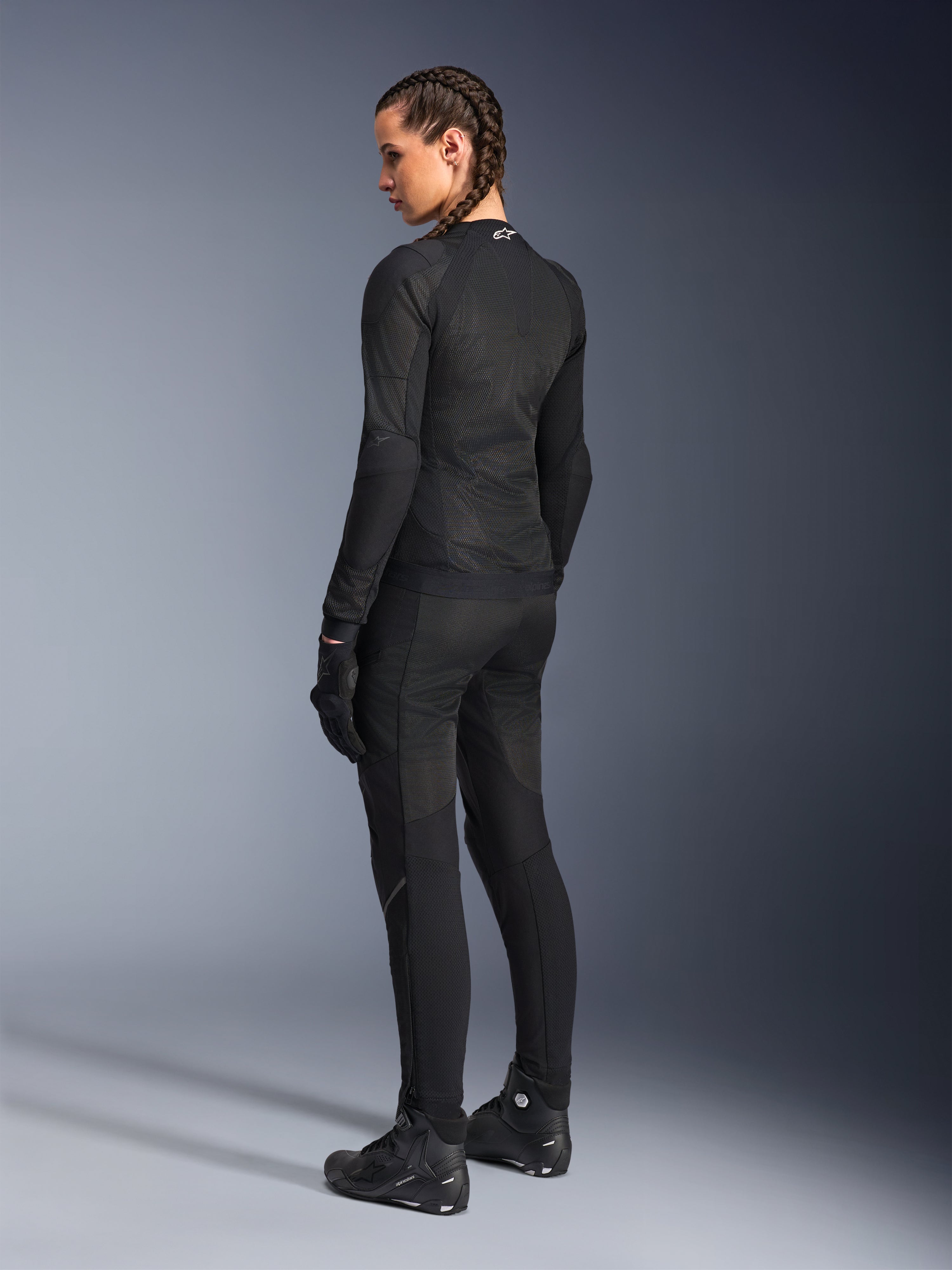 Alpinestars Stella Troop-Air motorjas voor dames, zwart, achteraanzicht, gedragen met bijpassende zwarte motorbroek, handschoenen en laarzen, slim-fit technische mesh-constructie voor rijden in de stad