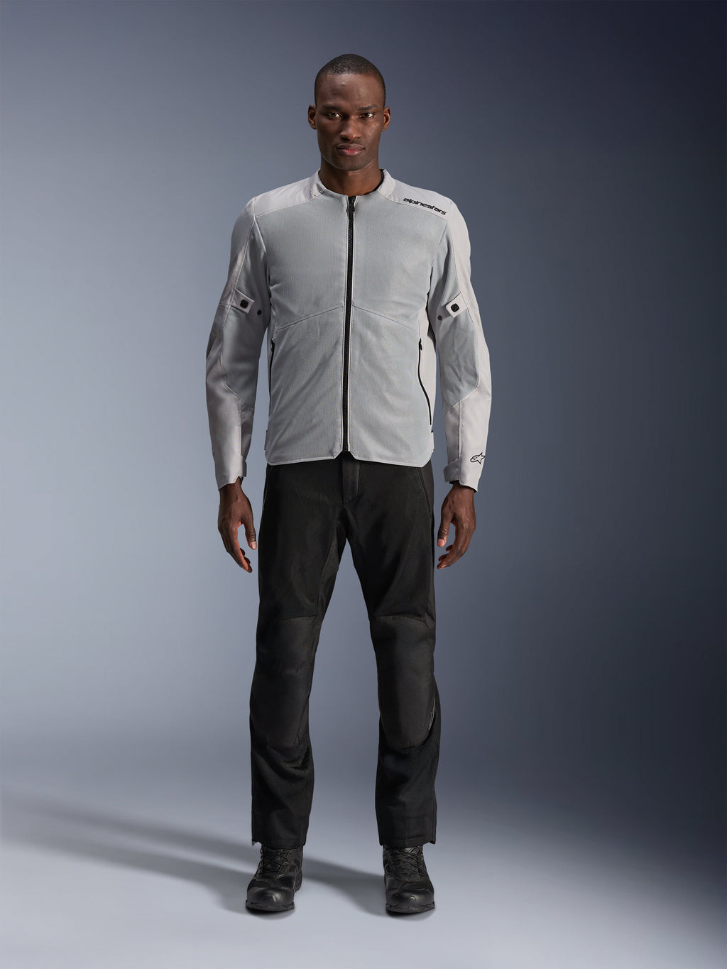 Alpinestars C-1 Air Jacket in Silver, heren urban textiele motorjas met geventileerde mesh-panelen, gedragen door een model met zwarte motorbroek en zwarte laarzen, eigentijdse stijl voor woon-werkverkeer