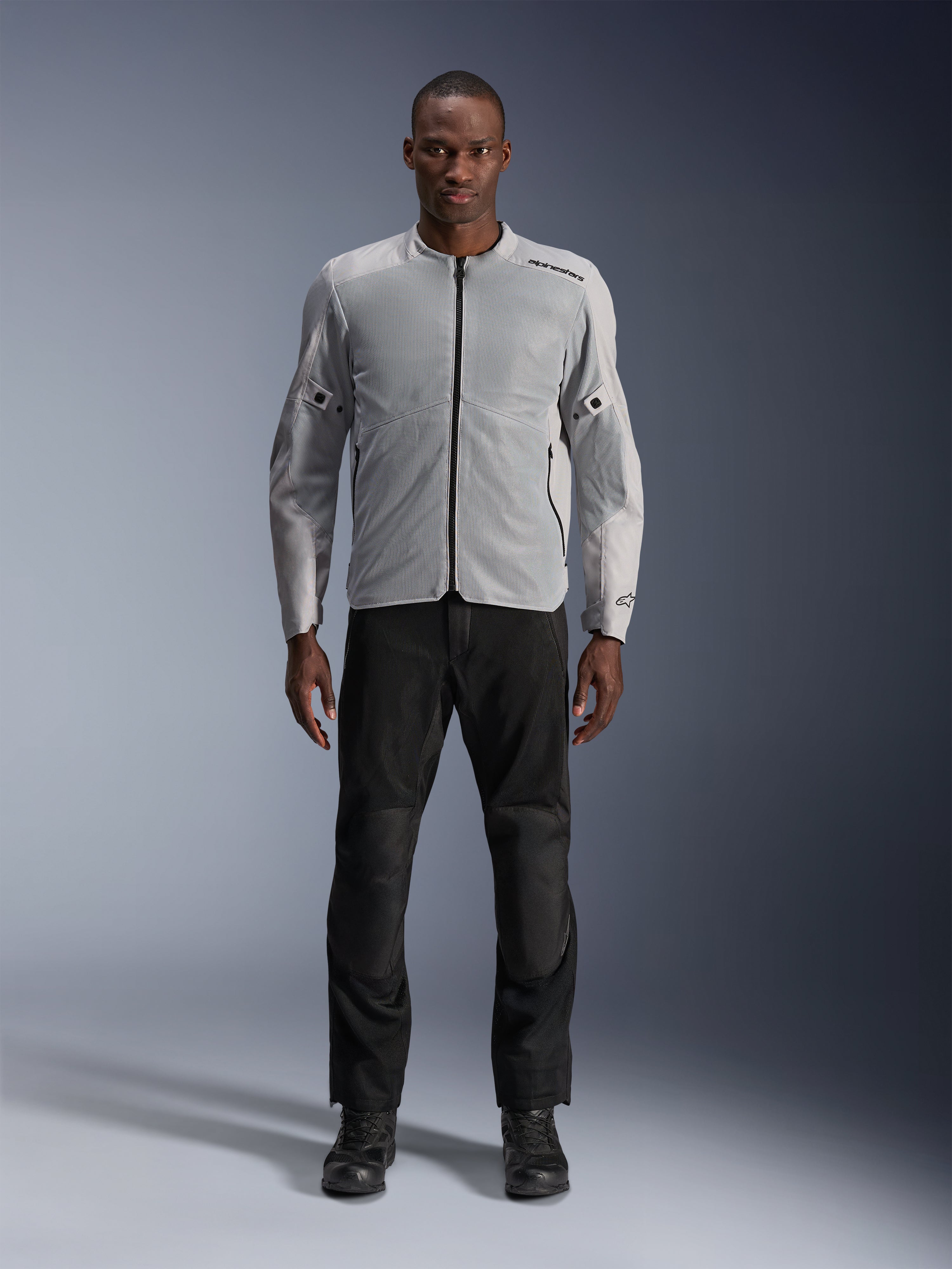 Alpinestars C-1 Air Jacket in Silver, heren urban textiele motorjas met geventileerde mesh-panelen, gedragen door een model met zwarte motorbroek en zwarte laarzen, eigentijdse stijl voor woon-werkverkeer