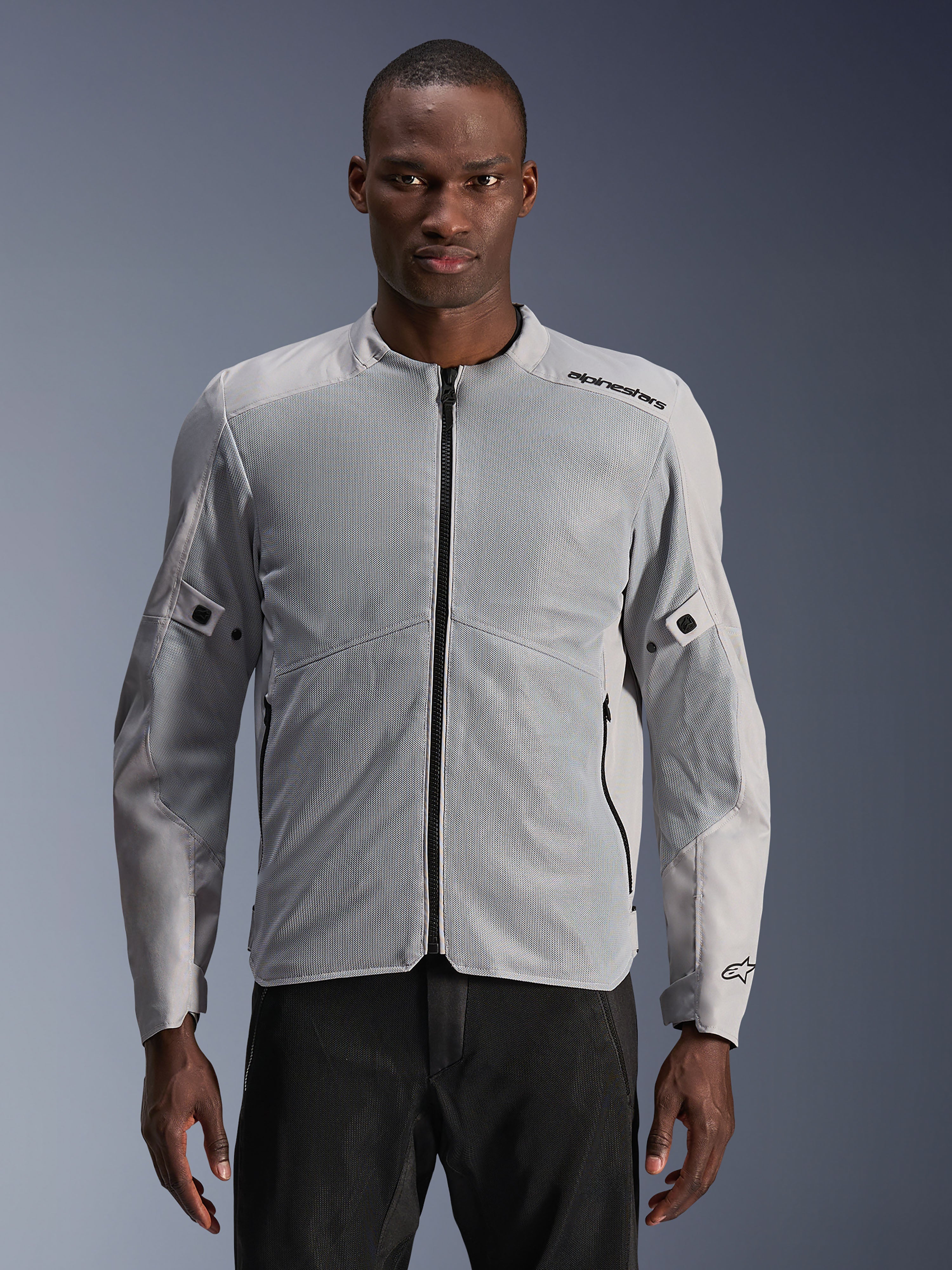 Alpinestars C-1 Air Jacket, urban motorjas, zilver en grijs, voorzien van grote tech mesh-panelen op de borst en mouwen, zwarte centrale rits, minimalistische branding op de schouder, lichtgewicht en geventileerd ontwerp voor woon-werkverkeer, model draagt de jas