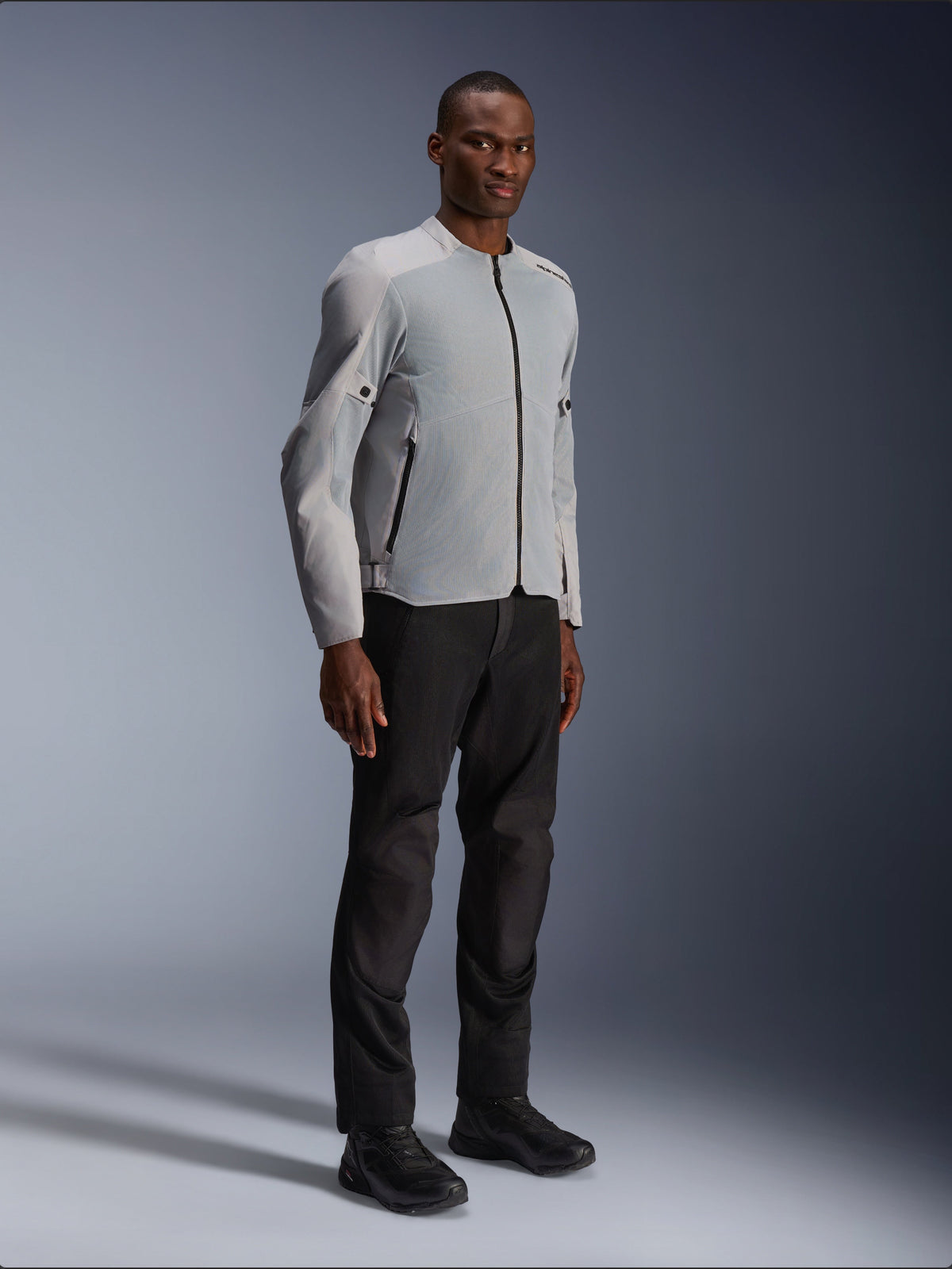 Alpinestars C-1 Air Jacket in zilver en grijs, urban motorjas, lichtgewicht textiel- en meshconstructie, gedragen met zwarte motorbroek en zwarte schoenen, strak eigentijds ontwerp voor stadsritten