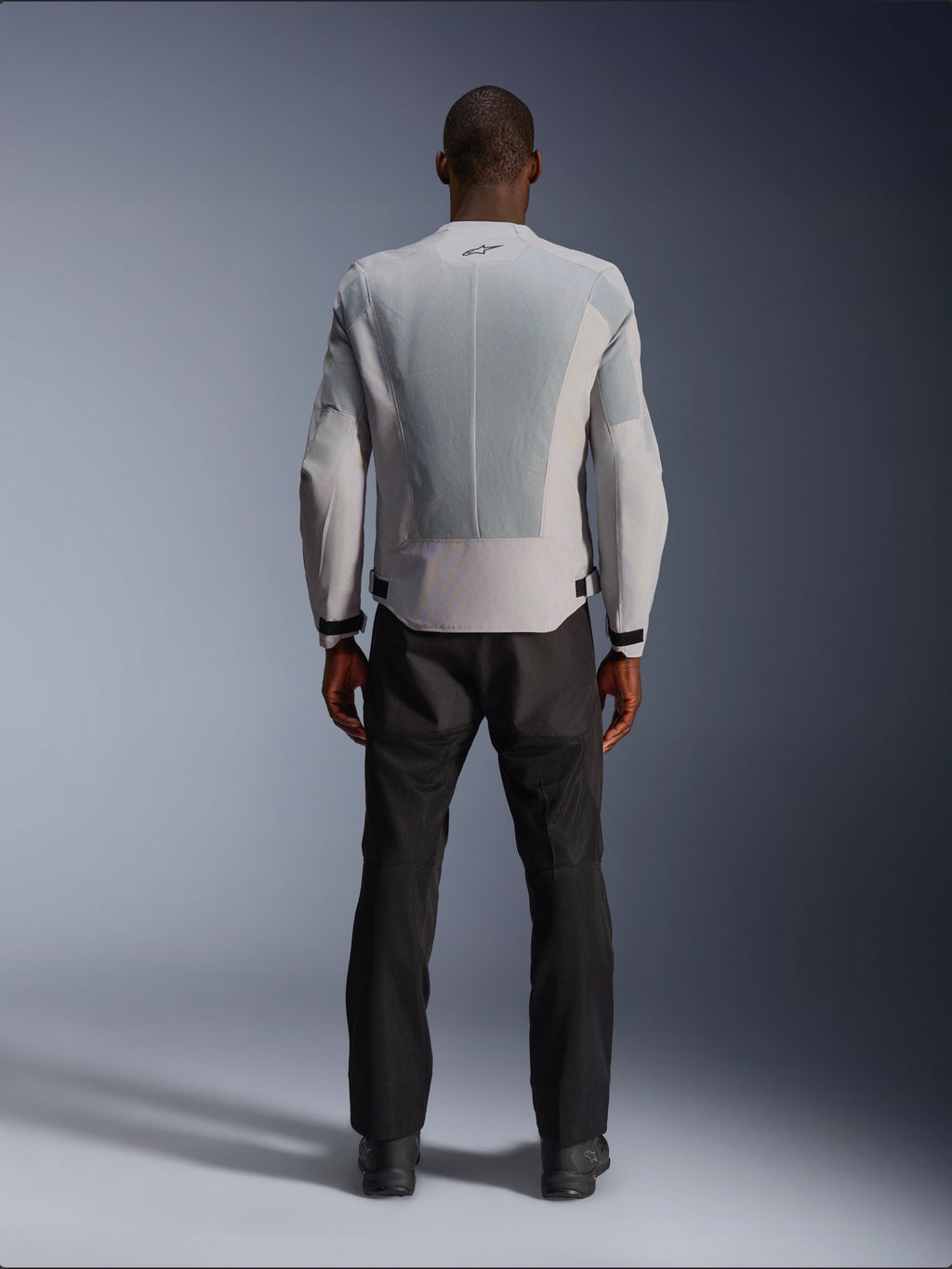Alpinestars C-1 Air Jacket in Silver, vanaf de achterkant gezien op een mannelijk model, textiele motorjas met grote tech mesh ventilatiepanelen, klein zwart logo in de nek en tailleverstellers, gedragen met een zwarte motorbroek voor een urban contemporary look.