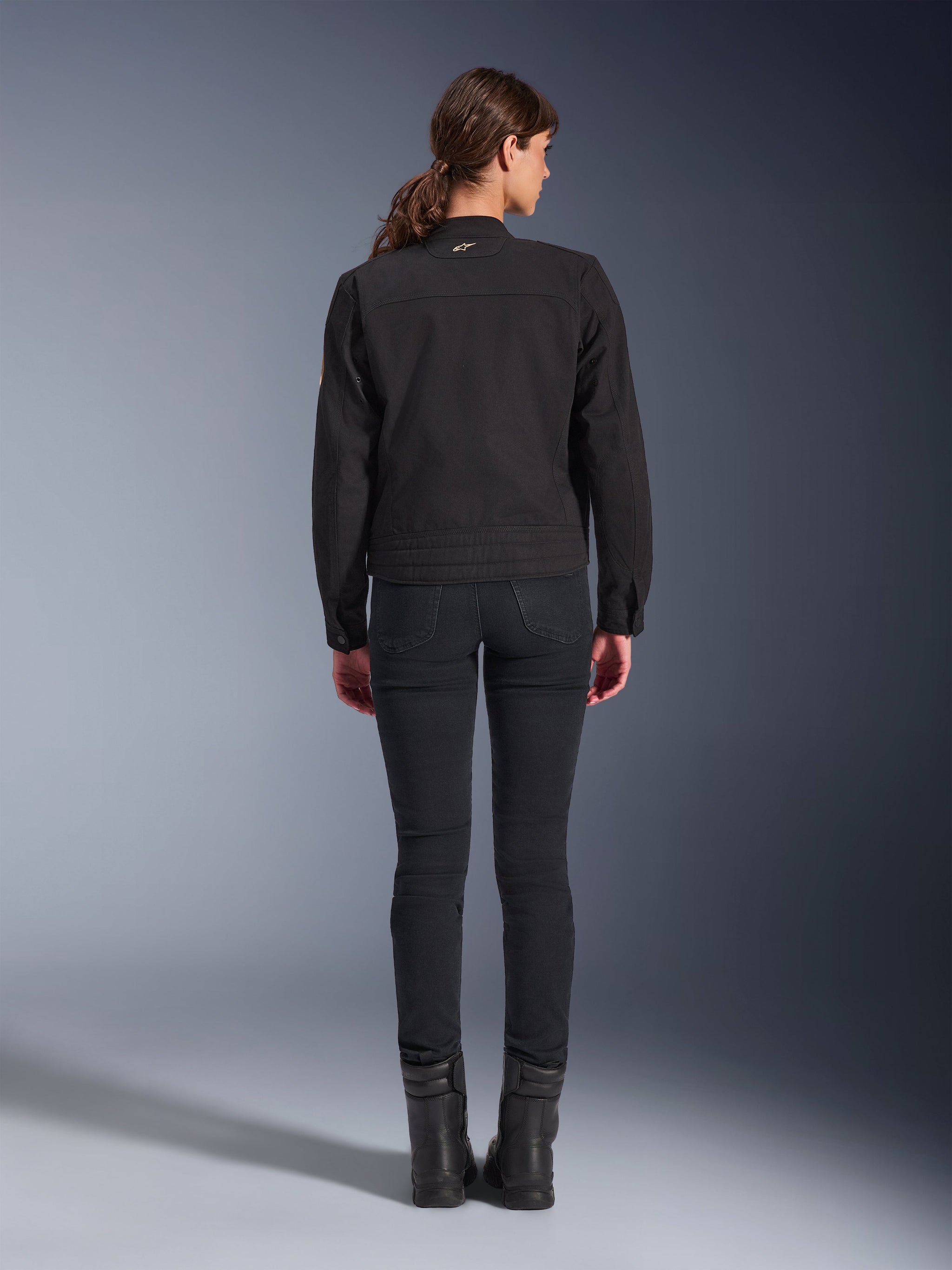 Alpinestars Stella Grace Jacket, Women's Urban Motorcycle Jacket, Black, back view showing workwear-inspired design, worn with black slim-fit pants and black boots, studio shot