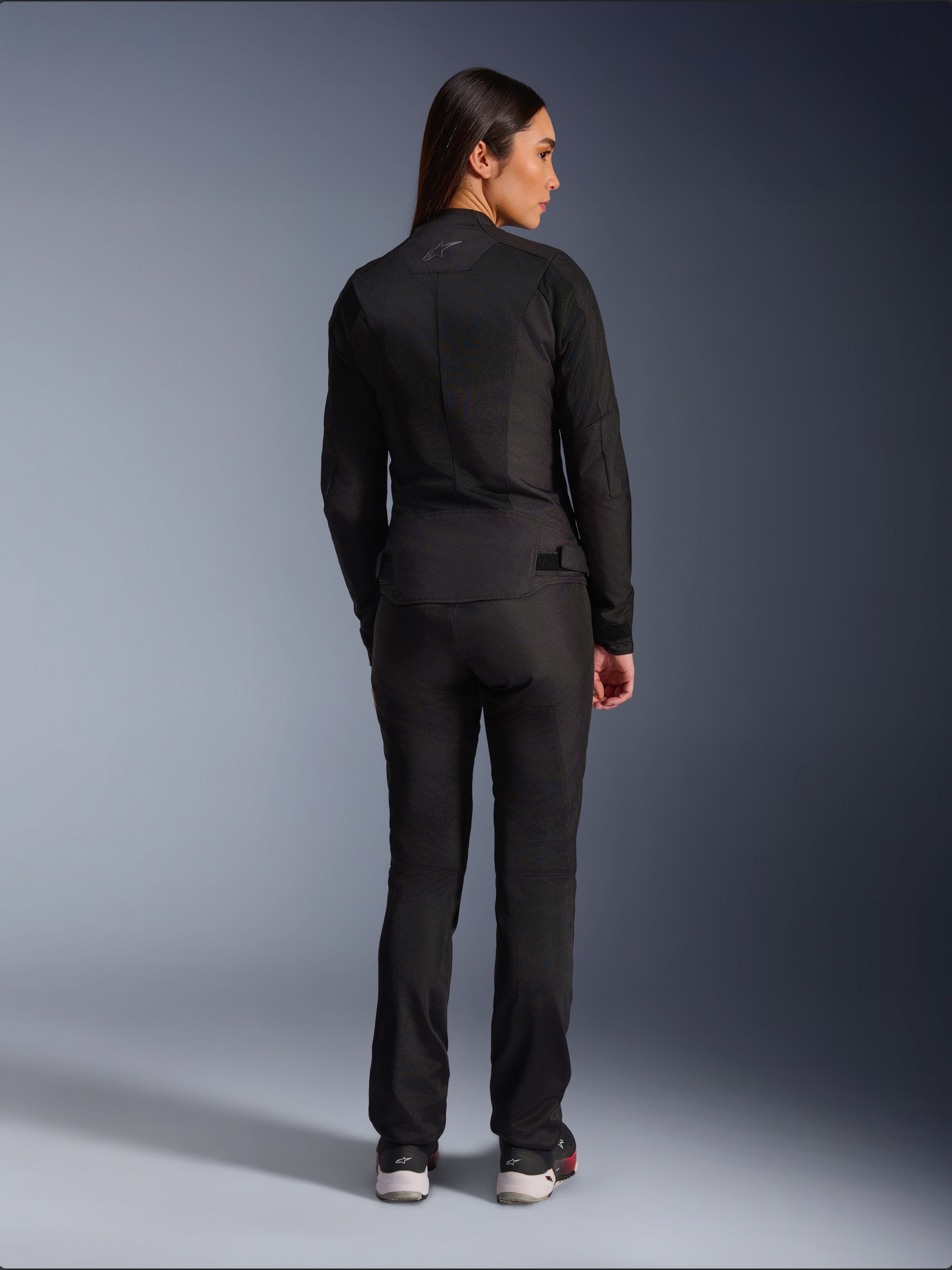 Alpinestars Stella C-1 Air Jacket, textiel motorjas voor dames, zwart, achteraanzicht met mesh-constructie en subtiel logo op de bovenrug, gedragen met bijpassende zwarte motorbroek, urban eigentijdse stijl