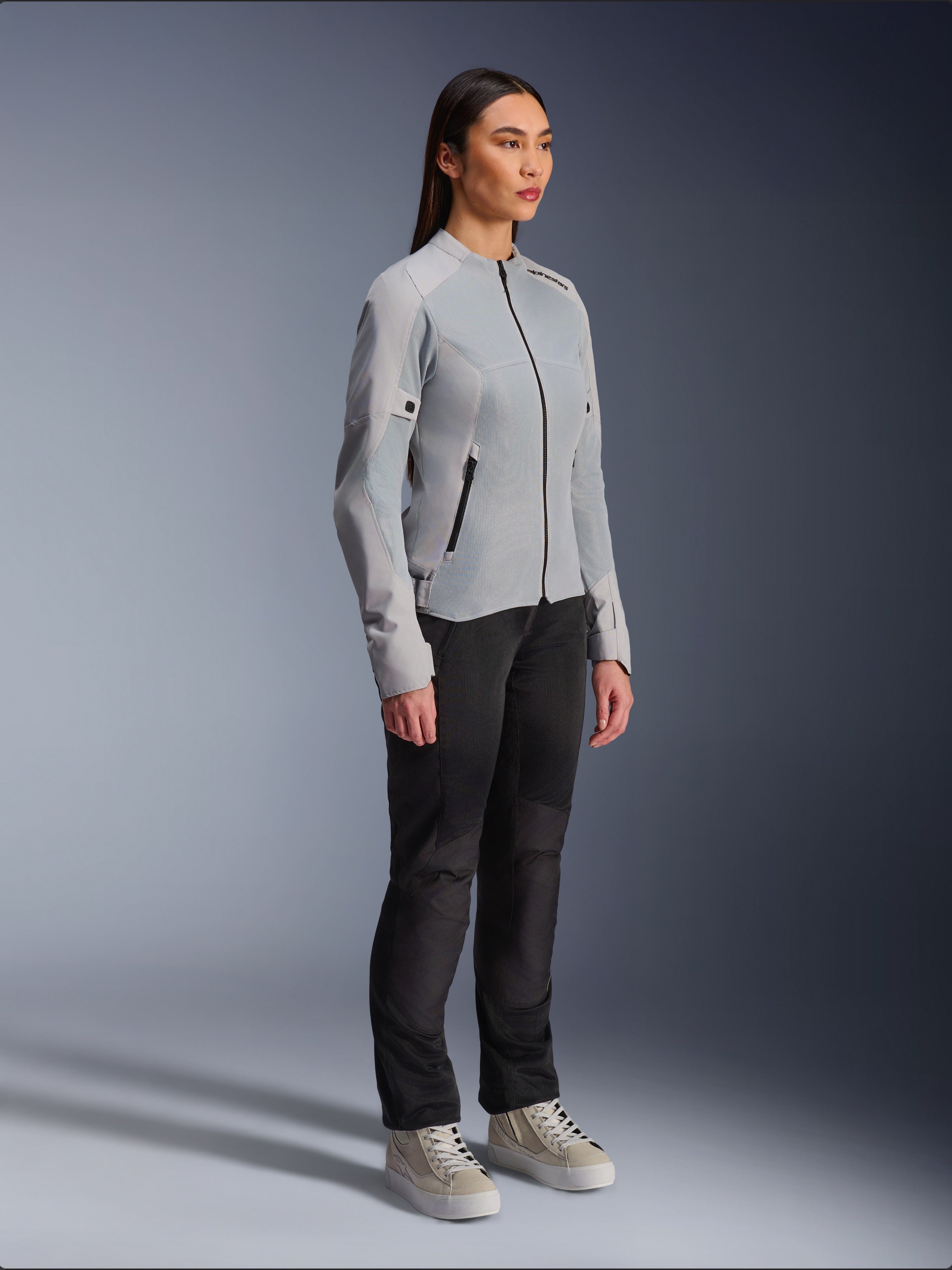 Vrouw draagt de Alpinestars Stella C-1 Air Jas in Silver, lichtgewicht motorjas van textiel en mesh, gecombineerd met een zwarte motorbroek en casual sneakers, strakke urban rij-esthetiek.