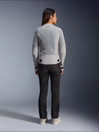 Vrouw draagt Alpinestars Stella C-1 Air Jacket in Silver, achteraanzicht, met grote tech mesh-panelen voor ventilatie en een reflecterend ster-logo, gecombineerd met een zwarte motorbroek en witte sneakers, urban hedendaagse motoruitrusting