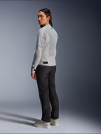 Vrouw die de Alpinestars Stella C-1 Air Jas in Silver draagt, achter- en zijaanzicht met tech mesh-panelen en reflecterend logo op de schouder, gecombineerd met een zwarte motorbroek en beige sneakers, eigentijdse urban rijstijl