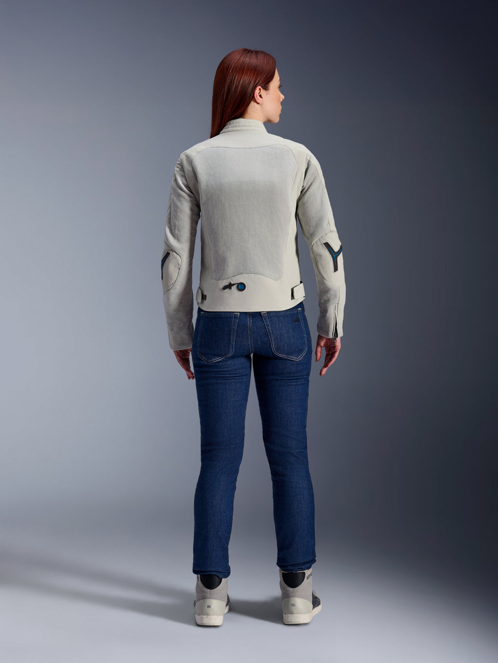 Alpinestars Stella Circal-1 Air damesmotorjas in Metal Gray en Methyl Blue, achteraanzicht, voorzien van grote mesh airflow-panelen op de rug en mouwen, gedragen met een donkerblauwe denim jeans en grijze motorschoenen voor een moderne urban motorlook.