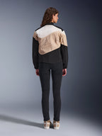 Alpinestars Stella Moshell Jacket, dames urban motorjas, achteraanzicht, asymmetrisch ontwerp in Black Sand en Off White met grote grafische omtrek, gedragen met zwarte slim-fit broek en beige sneakers, urban motoruitrusting