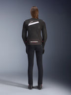 Alpinestars Stella T-GP Plus R V4 Airflow Jacket, zwart en wit, achteraanzicht met uitgebreide mesh ventilatiepanelen en Alpinestars-branding, gedragen door een vrouwelijke rijder met een slim-fit zwarte motorbroek en laarzen, sportieve textiele motoruitrusting voor dames