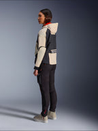 Alpinestars Molly Air Jacket, dames motorjas, Black Almond, met een capuchon, crèmekleurige mouwen en een zwarte romp, gedragen met een zwarte motorbroek en beige sneakers, urban contemporary stijl.