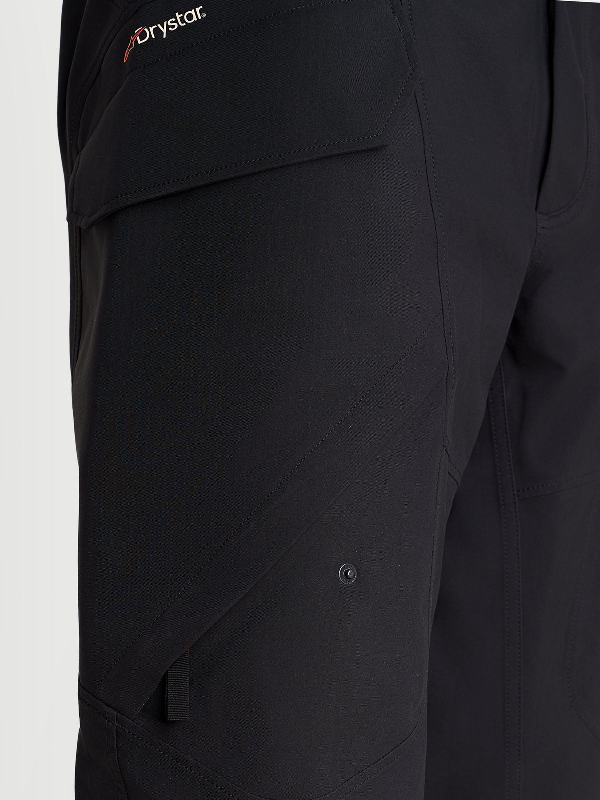 Alpinestars Juggernaut V2 Drystar broek, urban motorbroek, zwart, detailopname met de zijdakzak en Drystar-branding