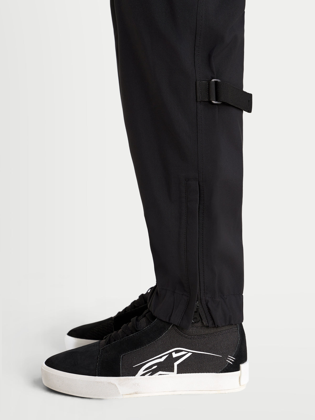 Alpinestars Juggernaut V2 Drystar broek, urban contemporary motorbroek in zwart, detailopname van het onderbeen en de elastische zoom met ritssluiting
