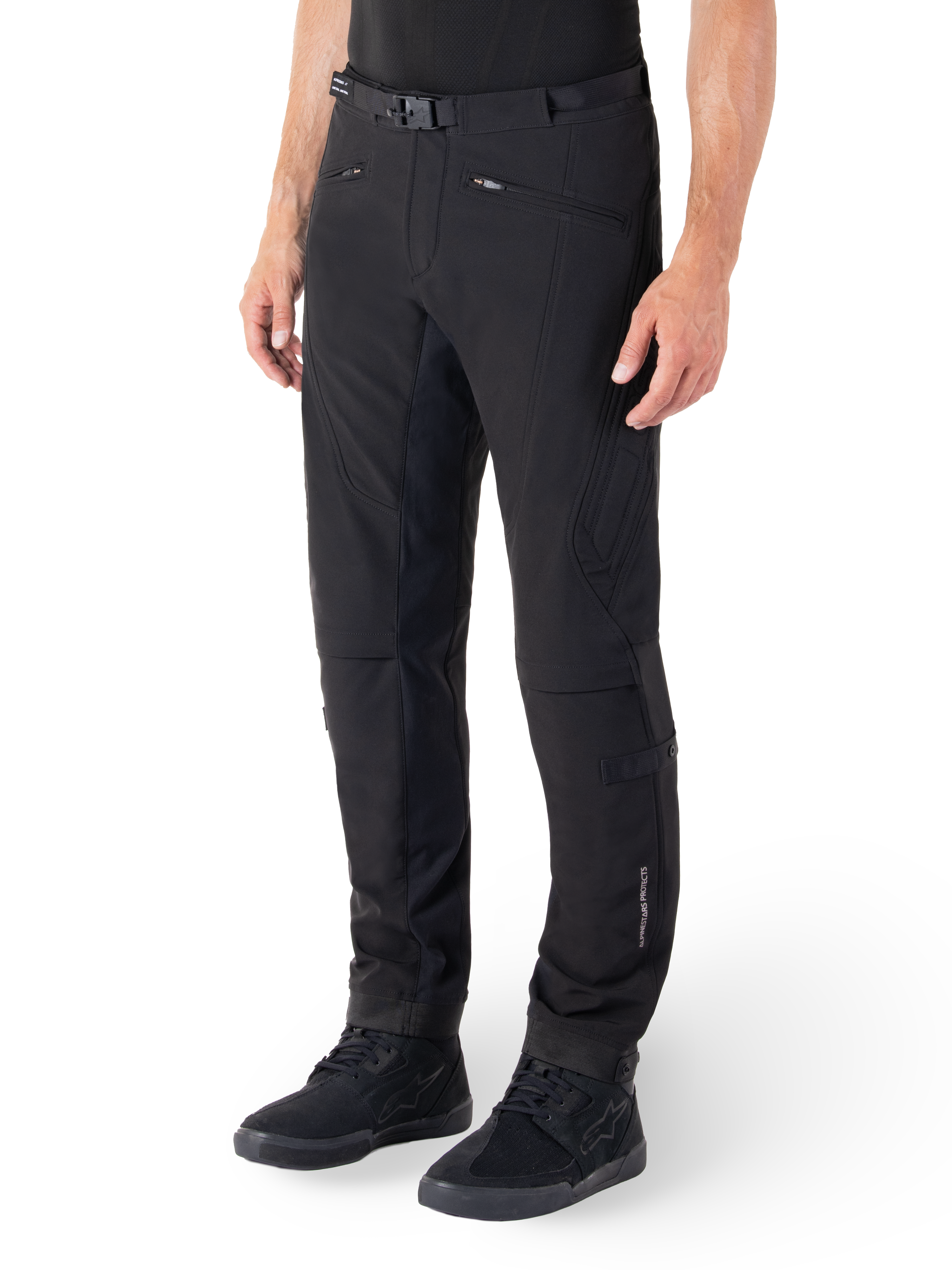 Alpinestars Alden broek, stedelijke motorbroek, zwart, technische softshell-stof met een regular fit, voorzien van een magnetische gesp in de taille, gewatteerde zijpanelen, zakken met ritssluiting en subtiele branding op het onderbeen, gedragen met zwarte motorschoenen