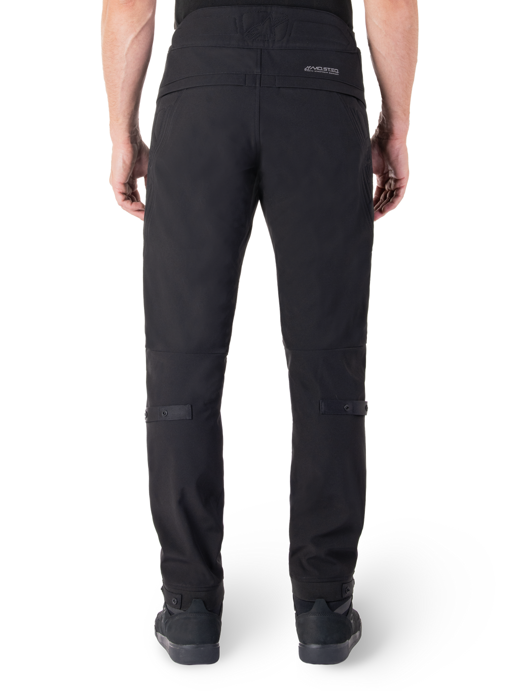 Alpinestars Alden broek, zwarte urban motorbroek, achteraanzicht, met reflecterend MO.ST.EQ.-woordmerk op de achterpas, slanke pasvorm onder de knie en volumeregelaars met drukknopen op de kuiten en manchetten, streetwear-geïnspireerd technisch textielontwerp.