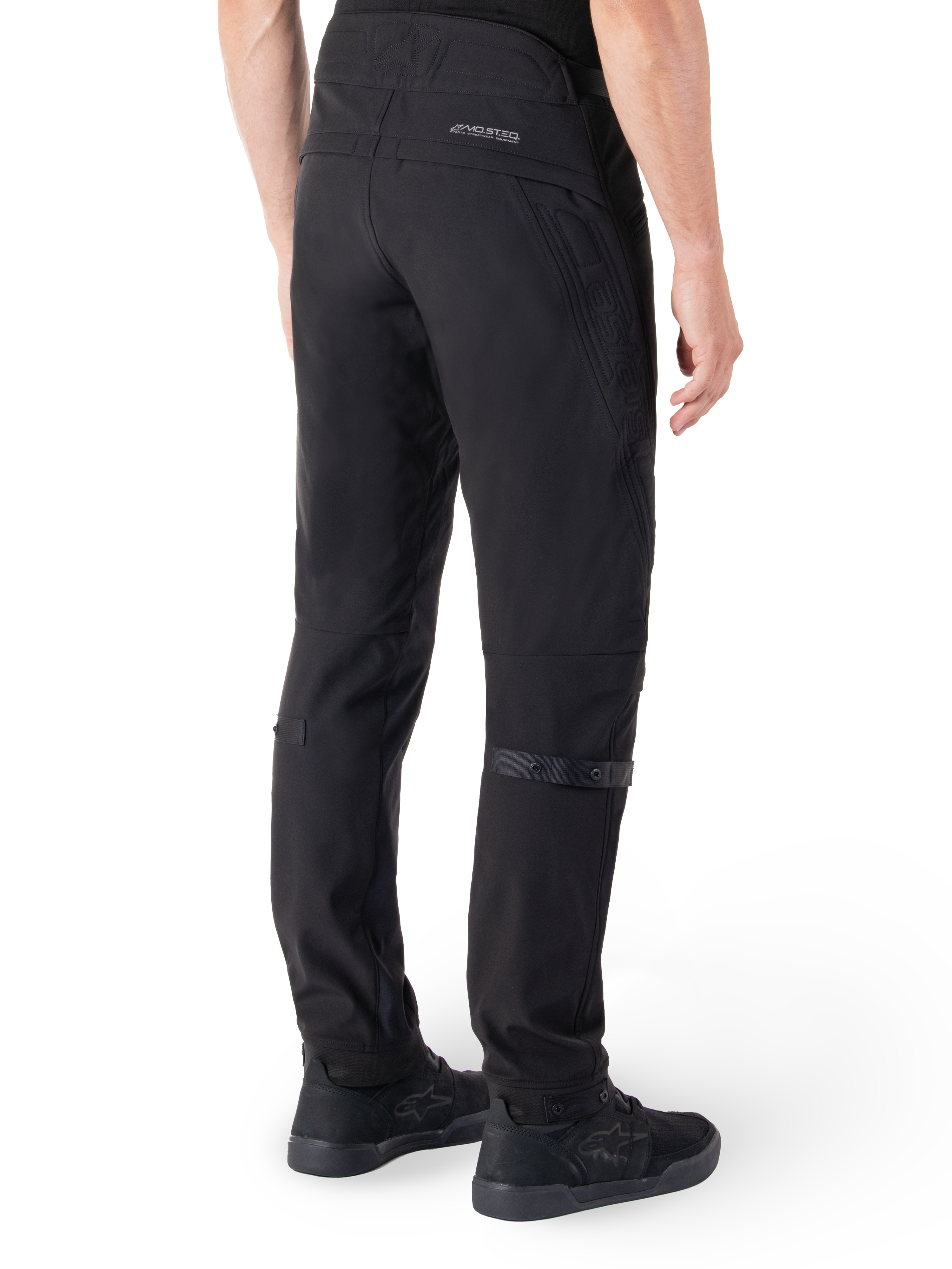 Alpinestars Alden broek, urban motorbroek, zwart, achteraanzicht met technische softshell stof en gewatteerde details, MO.ST.EQ. reflecterende branding op de achterpas en verstelbare kuitbanden, gecombineerd met zwarte motorschoenen