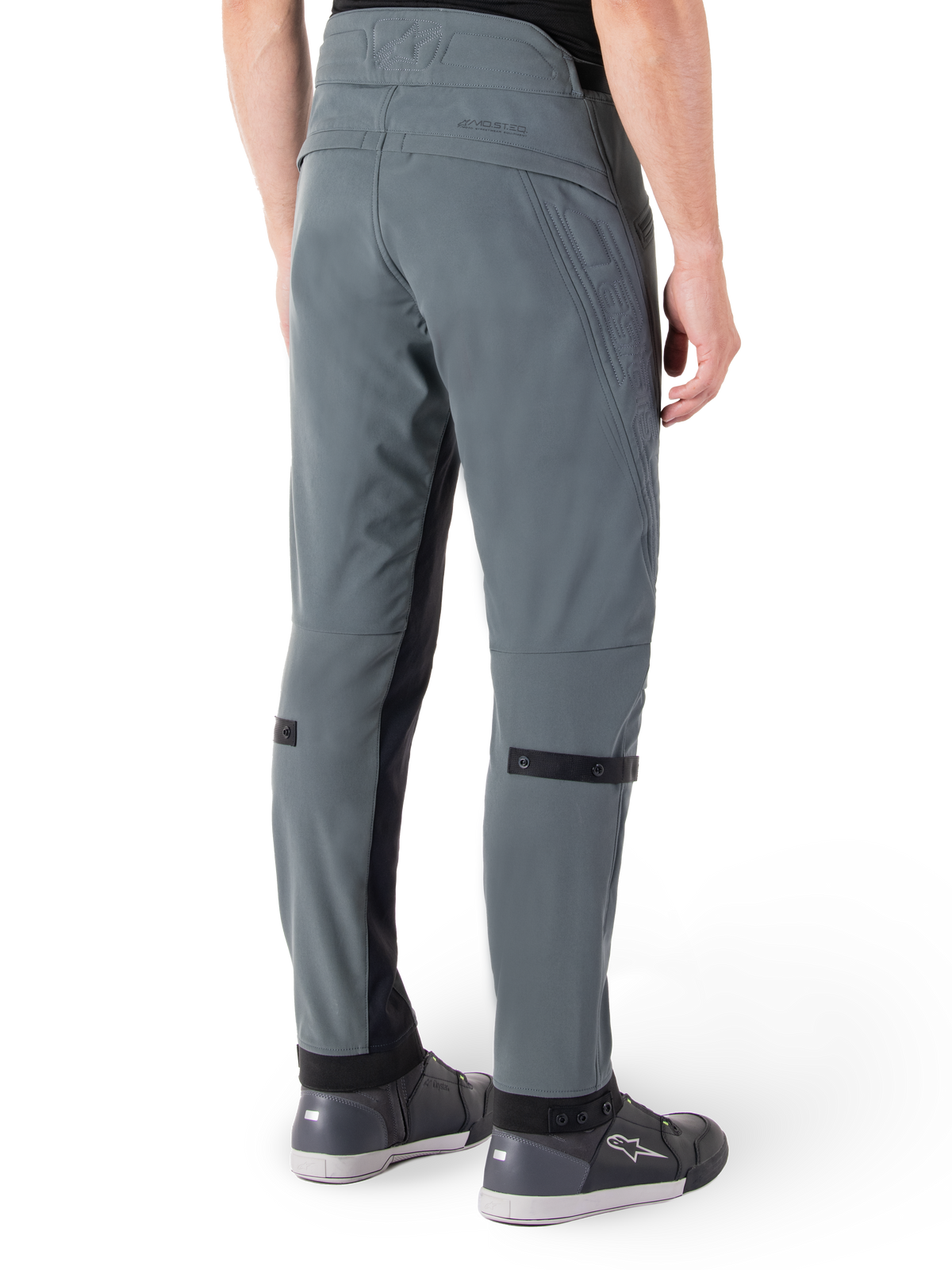 Alpinestars Alden broek, Urban Gray, achteraanzicht, op streetwear geïnspireerde technische motorbroek met gewatteerde details in de taille en zwarte kuitbanden, gecombineerd met grijze motorschoenen, moderne stedelijke motoruitrusting