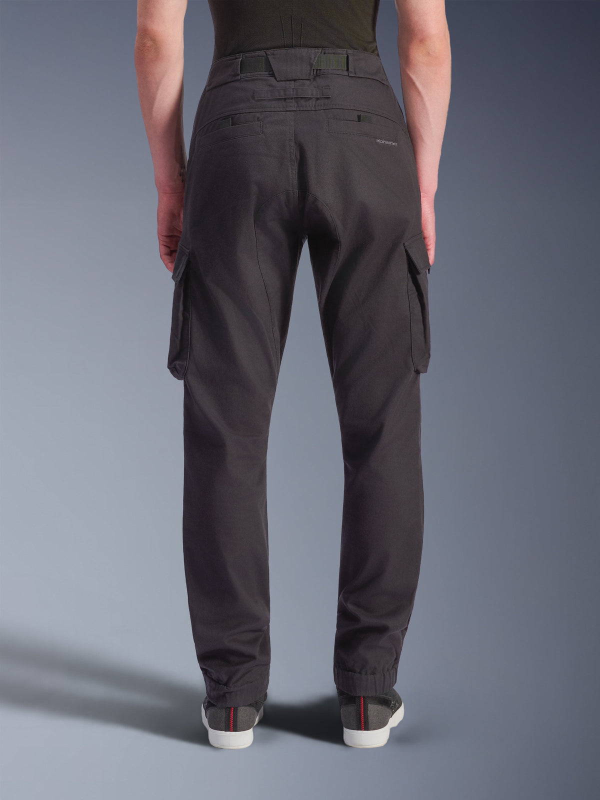 Alpinestars Flex-AST Cargo Pants, zwarte technische motorbroek, achteraanzicht met een normale toelopende pasvorm en elastische zomen, grote cargozakken en subtiele branding, ontworpen voor stedelijk rijden