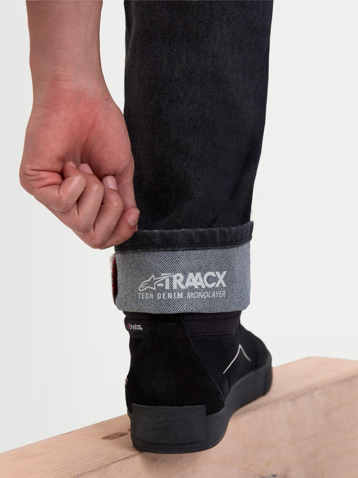 Alpinestars Flex Ast 8 Denim broek, urban motorjeans in zwart, detailopname van de omgeslagen broekspijp met A-TRAACX enkellaags technische denimconstructie en binnenbranding