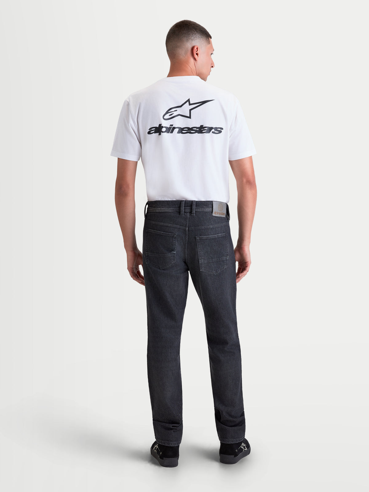 Alpinestars Flex Ast 8 Denim broek, heren motorjeans in Used Black, achteraanzicht op model met AA-gecertificeerde single-layer denim, leren label op de achterkant en borduurwerk op de achterzak