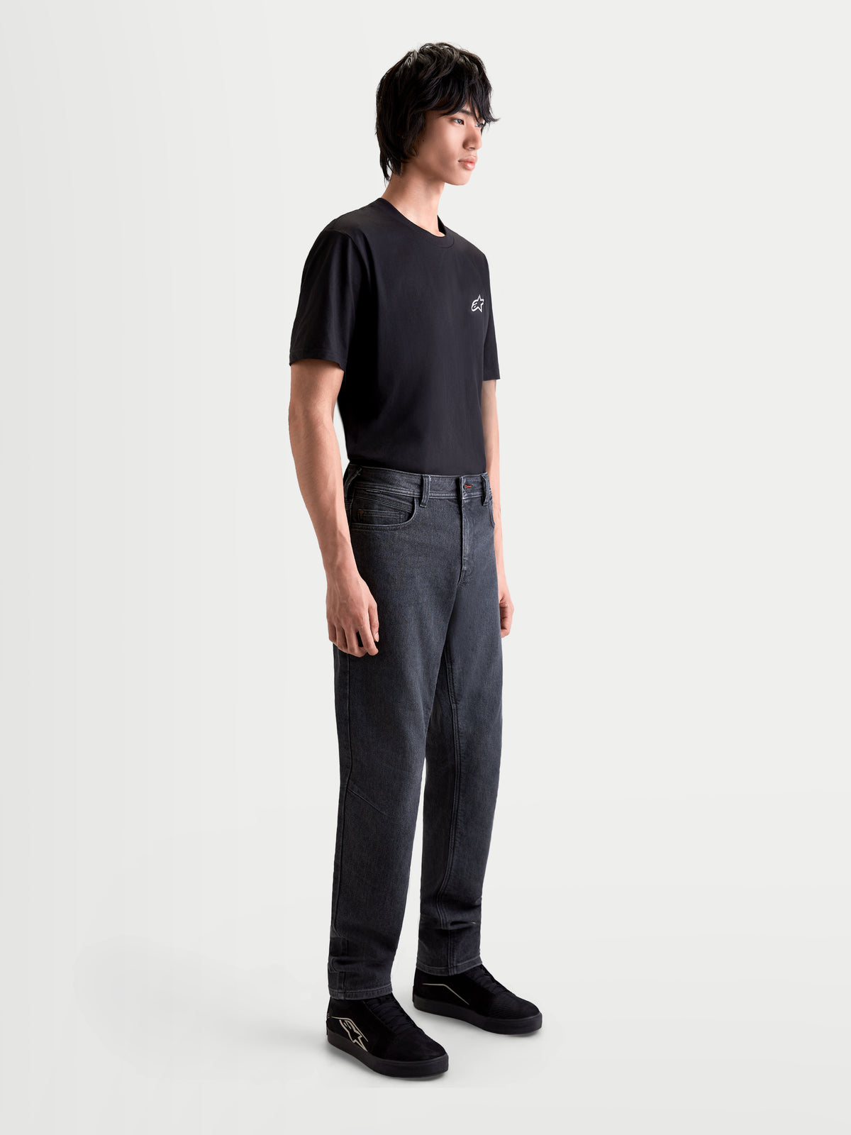 Alpinestars Flex Ast 7 Denim broek, urban motorjeans voor heren in vervaagd zwart, zijaanzicht op model met zwart t-shirt en schoenen, AA-gecertificeerde single-layer technische denimconstructie