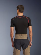 Alpinestars Flex-AST Explorer broek, achteraanzicht op model, Walnut Black, voorzien van tan textiel met versterkte zwarte zitpanelen en een elastische tailleband, gecombineerd met een zwarte basislaag met korte mouwen en rode stiksels