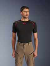 Alpinestars Flex-AST Explorer broek, adventure motorbroek, Walnut Black, gedragen door een model met een zwart base layer shirt, voorzien van diagonale cargozakken met ritssluiting en een duurzame stretch textielconstructie.