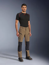 Alpinestars Flex-AST Explorer Pants, Walnut Black adventure motorbroek, gedragen door een mannelijk model met een zwarte basislaag met korte mouwen en adventure-laarzen, voorzien van cargozakken met ritssluiting en verstevigde kniepanelen, technische uitrusting voor dual-sport- en toerrijders.